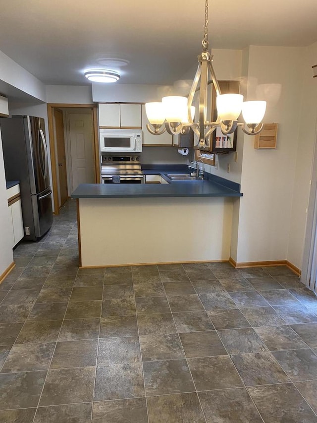 kitchen with stainless steel appliances, sink, kitchen peninsula, an inviting chandelier, and decorative light fixtures