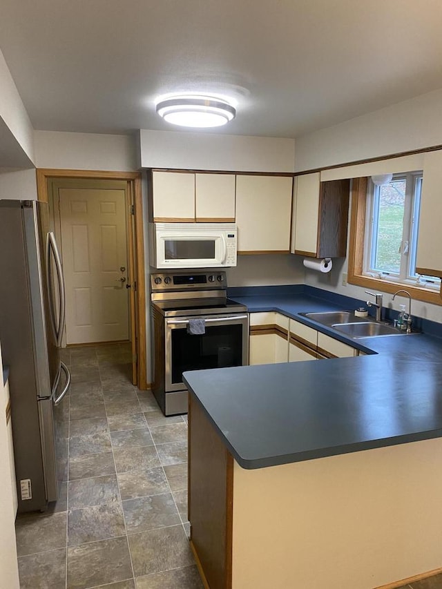 kitchen with kitchen peninsula, appliances with stainless steel finishes, and sink