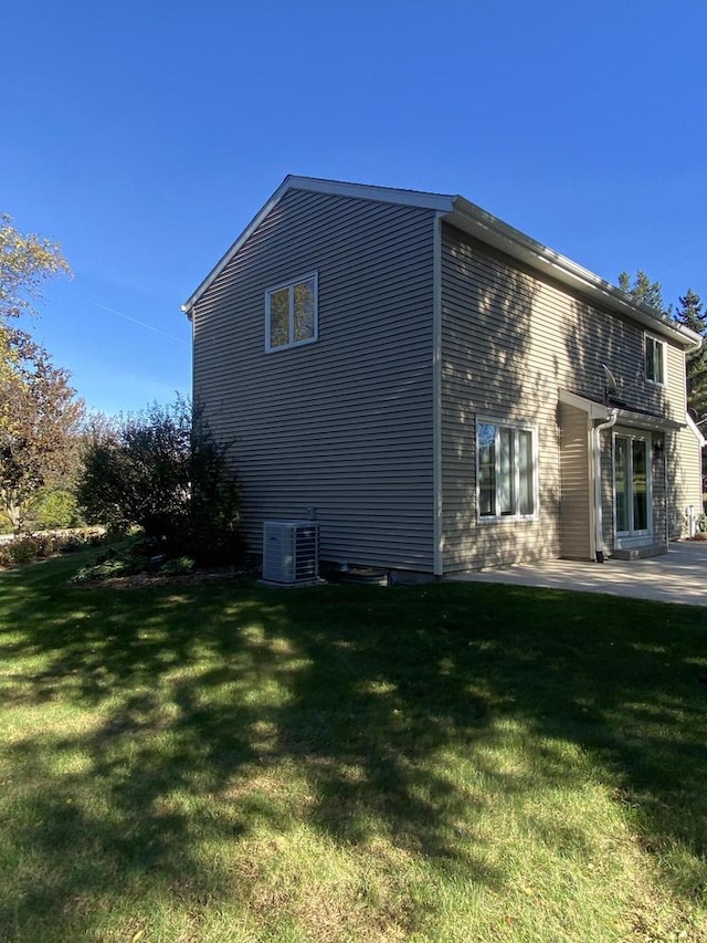 view of property exterior with central AC unit, a lawn, and a patio