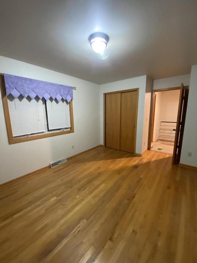 unfurnished bedroom with hardwood / wood-style floors, connected bathroom, and a closet