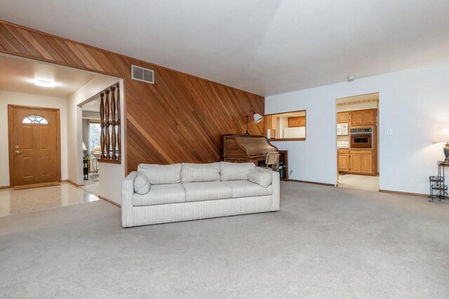 living room featuring wooden walls and light colored carpet