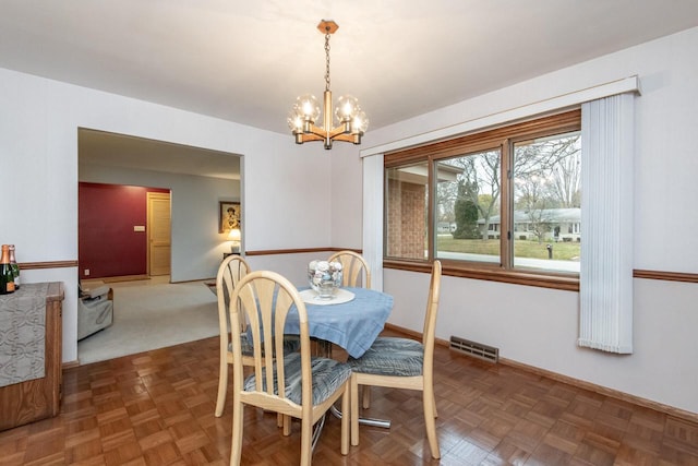 dining space featuring a chandelier and dark parquet flooring