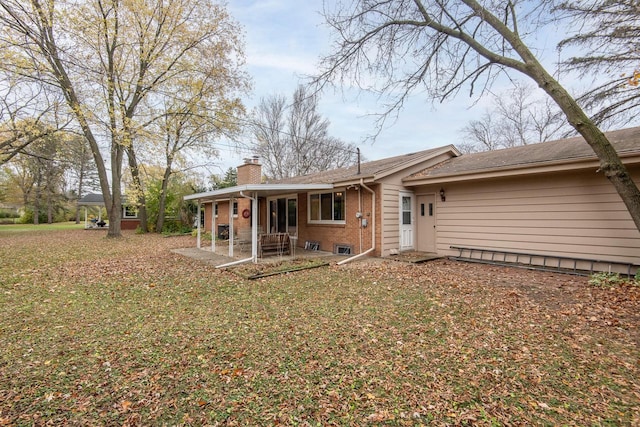 rear view of house with a lawn and a patio