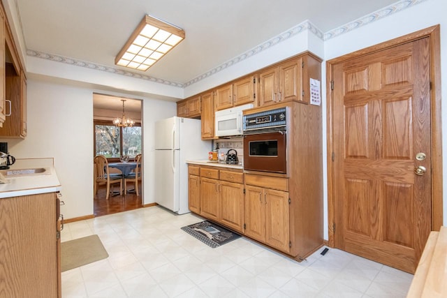 kitchen with a chandelier, pendant lighting, and white appliances