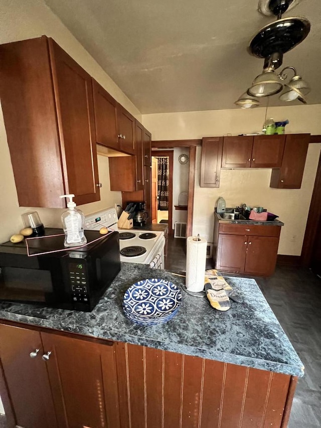 kitchen featuring white electric stove and dark stone countertops