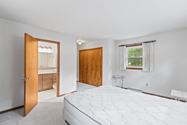 W11384 Bay Dr, Lodi, WI 53555 - bedroom with baseboard heating, connected bathroom, light colored carpet, a closet, and baseboards