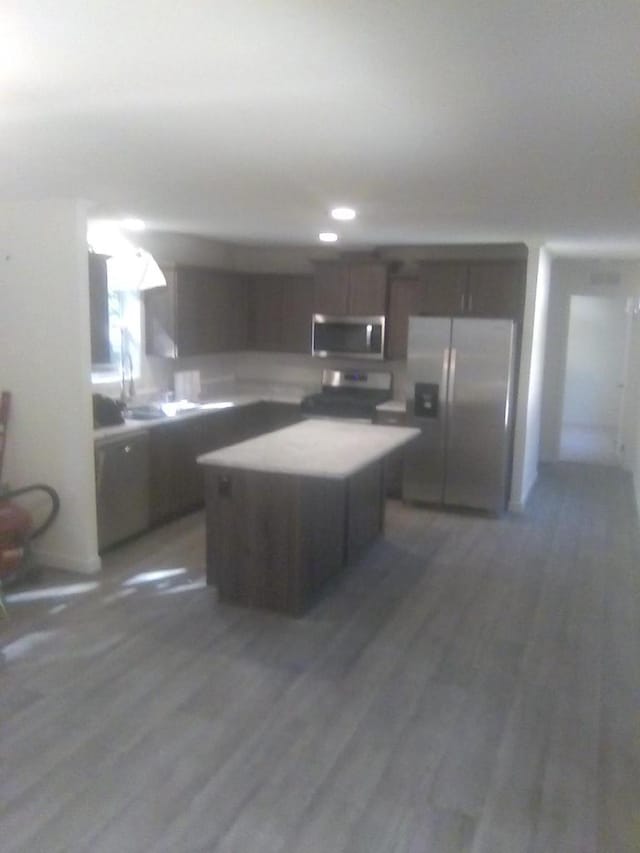 kitchen with a kitchen island, appliances with stainless steel finishes, sink, dark hardwood / wood-style flooring, and dark brown cabinetry