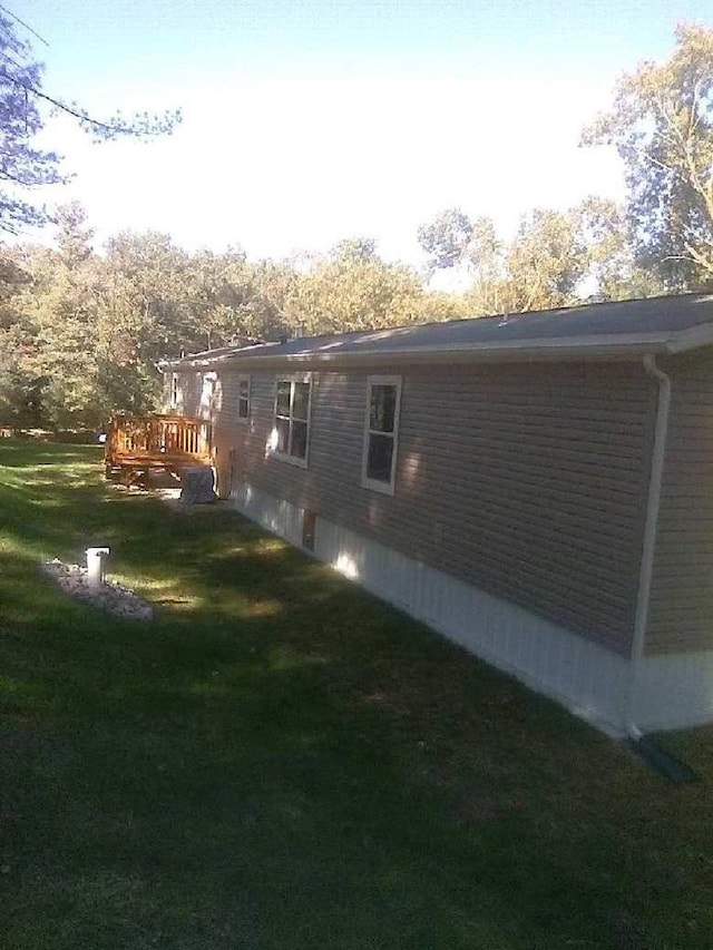 view of side of property with a wooden deck and a yard