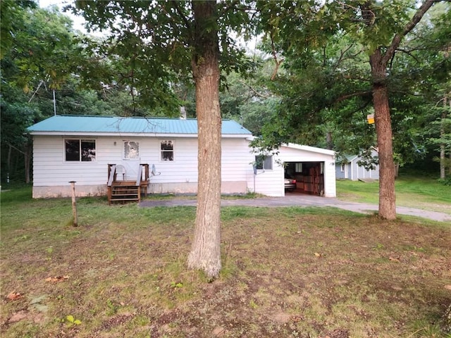 back of property with a garage, a lawn, and an outbuilding