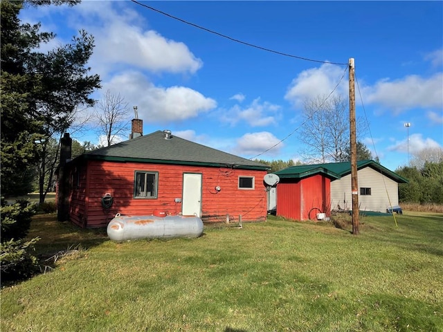 rear view of property with a lawn and a storage shed