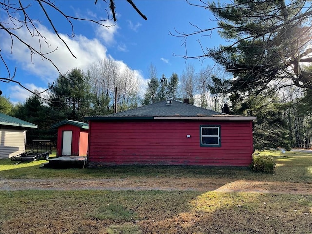 view of property exterior featuring a storage unit and a lawn