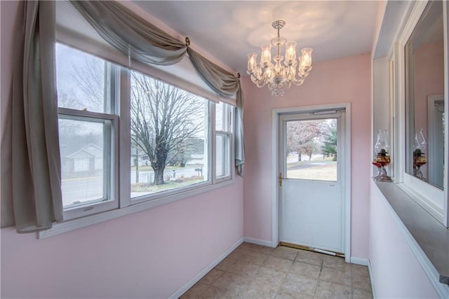 doorway featuring a chandelier and baseboards