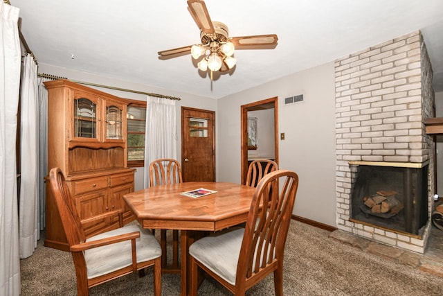 carpeted dining space with ceiling fan and a brick fireplace