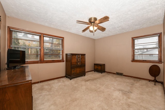 unfurnished office featuring a textured ceiling, light carpet, and ceiling fan