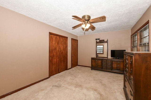 bedroom with ceiling fan, a textured ceiling, and light colored carpet