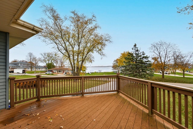 wooden terrace featuring a water view and a yard