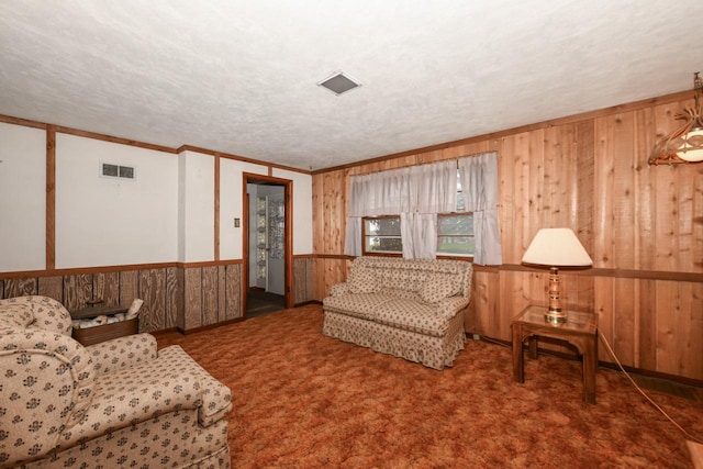 carpeted living room with ornamental molding, wooden walls, and a textured ceiling