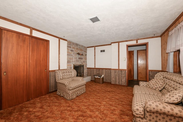 sitting room featuring a stone fireplace, a textured ceiling, and crown molding