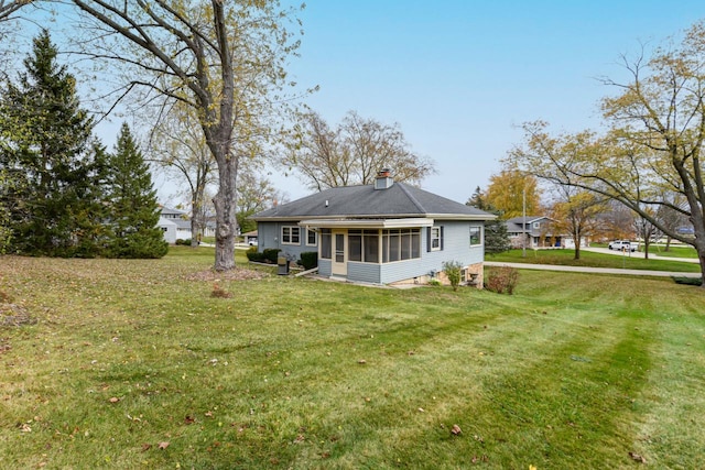 rear view of house featuring a sunroom and a lawn