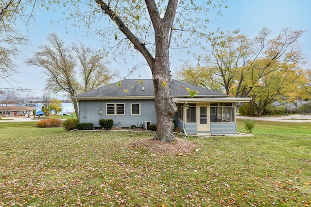 rear view of house featuring a sunroom and a lawn