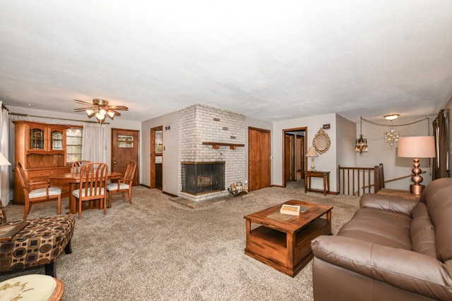 living room with a brick fireplace, carpet, and ceiling fan with notable chandelier