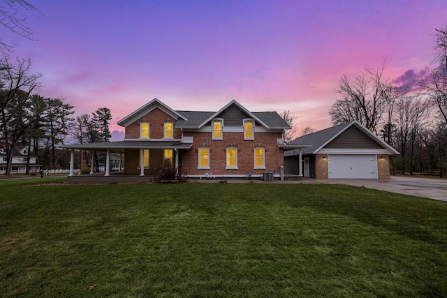 view of front of property with a garage, central AC unit, covered porch, and a lawn