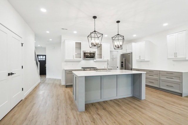 kitchen featuring a center island with sink, gray cabinets, stainless steel appliances, and light hardwood / wood-style flooring