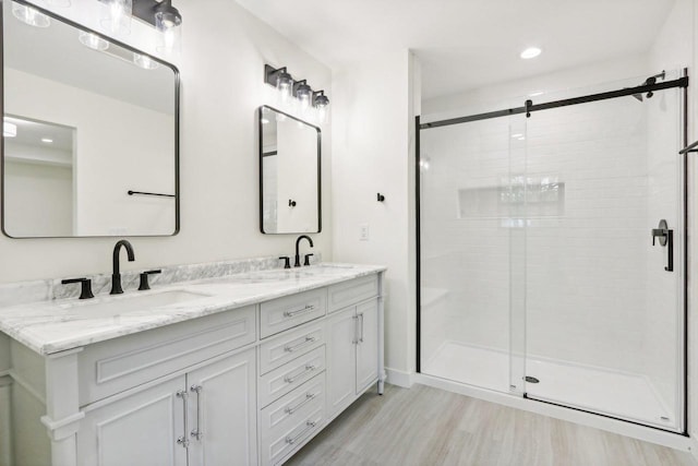 bathroom with wood-type flooring, vanity, and a shower with door