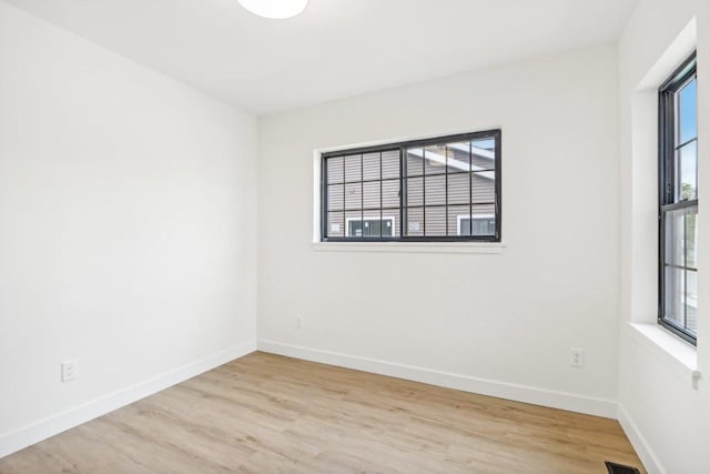 spare room featuring light wood-type flooring and a healthy amount of sunlight