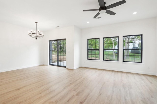 empty room featuring ceiling fan with notable chandelier and light wood-type flooring