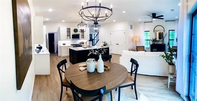 dining space featuring ceiling fan with notable chandelier and light hardwood / wood-style floors