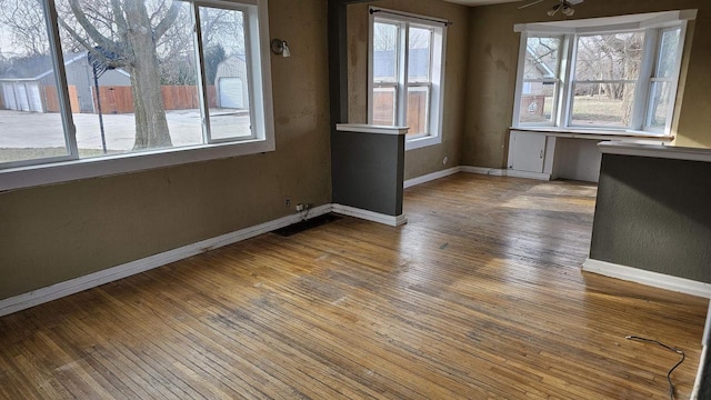 unfurnished dining area with ceiling fan, wood-type flooring, and a wealth of natural light