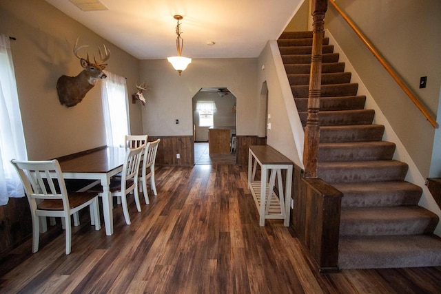 dining space featuring dark hardwood / wood-style flooring and wooden walls