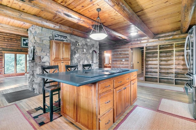 kitchen featuring a kitchen island, decorative light fixtures, a kitchen bar, beam ceiling, and light hardwood / wood-style floors