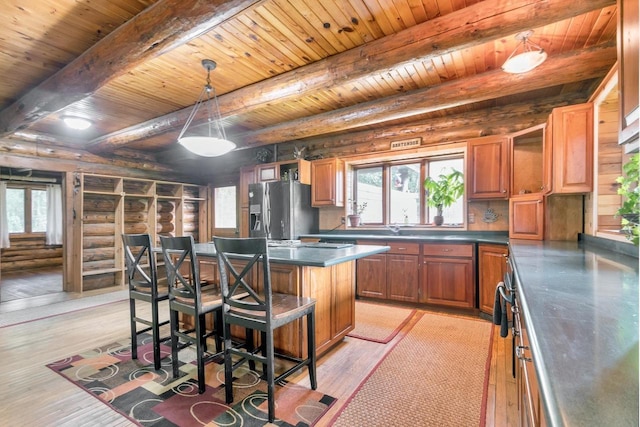 kitchen with light hardwood / wood-style floors, hanging light fixtures, a center island, and stainless steel fridge