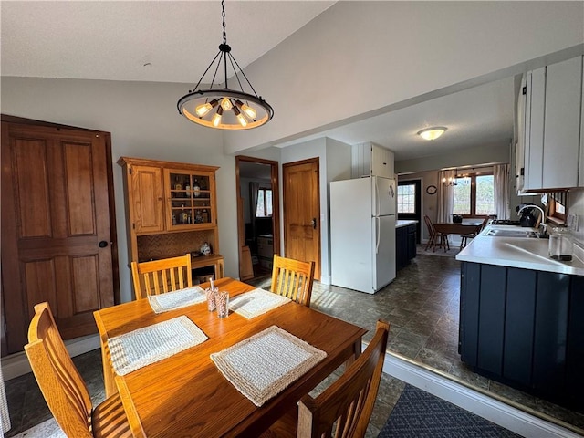 dining area with lofted ceiling, sink, and a notable chandelier