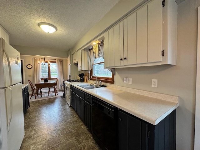 kitchen featuring dishwasher, sink, stainless steel gas stove, white fridge, and white cabinetry