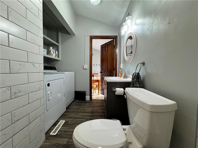 bathroom featuring hardwood / wood-style flooring, separate washer and dryer, vanity, toilet, and vaulted ceiling