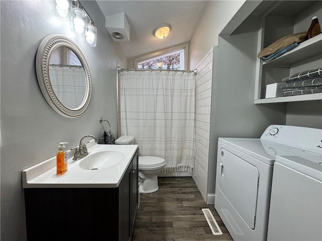 bathroom featuring vanity, a textured ceiling, hardwood / wood-style floors, toilet, and washing machine and dryer