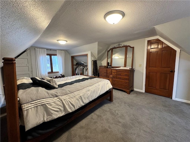 bedroom featuring a walk in closet, light colored carpet, a textured ceiling, and vaulted ceiling