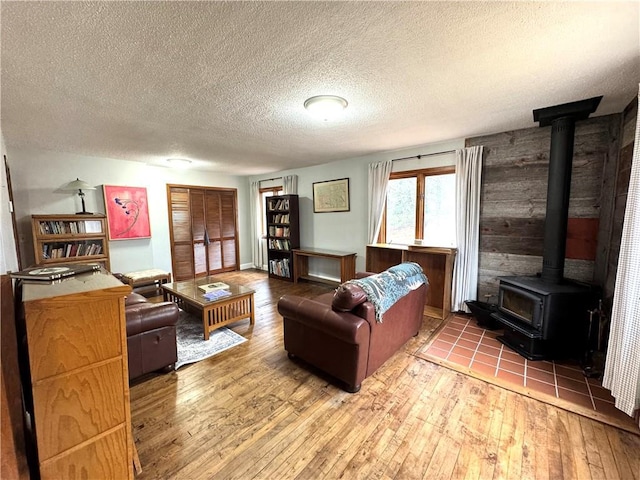 living room with wood-type flooring, a textured ceiling, and a wood stove