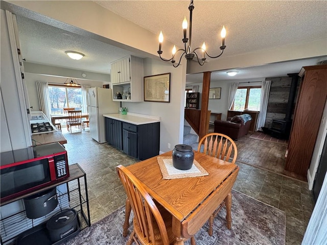 dining room with an inviting chandelier, a wealth of natural light, a textured ceiling, and dark hardwood / wood-style floors