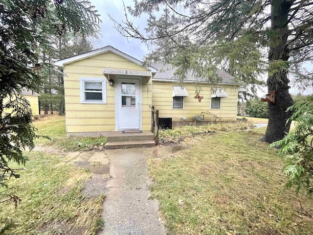 bungalow-style house featuring cooling unit and a front lawn