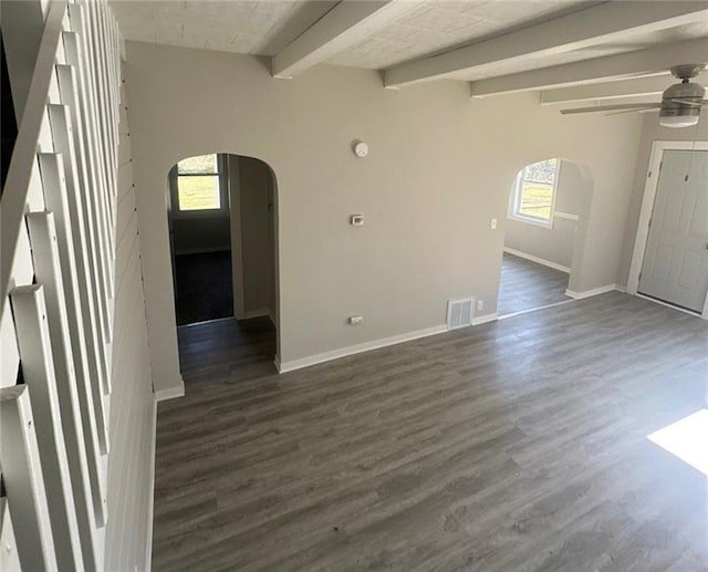 empty room with dark hardwood / wood-style flooring, vaulted ceiling with beams, and plenty of natural light