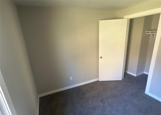 unfurnished bedroom featuring dark colored carpet and a closet