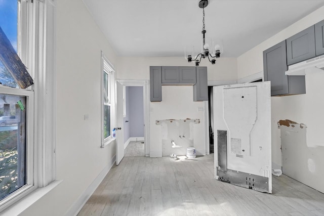 kitchen featuring hanging light fixtures, gray cabinetry, light wood-type flooring, and a notable chandelier