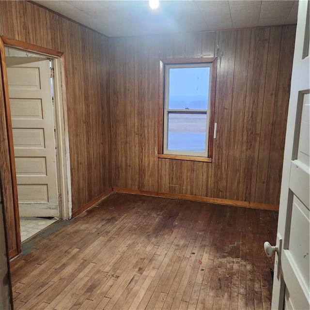 unfurnished room featuring wood walls and dark wood-type flooring