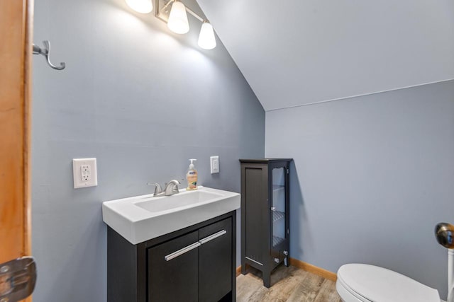 bathroom featuring lofted ceiling, hardwood / wood-style flooring, toilet, and vanity