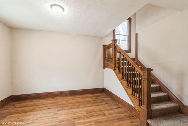 stairway featuring hardwood / wood-style floors, lofted ceiling, and a textured ceiling