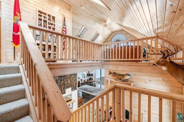 stairs with wood walls, lofted ceiling, ceiling fan, and wooden ceiling